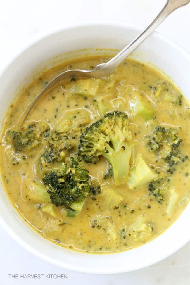 a white bowl filled with broccoli and cheese soup