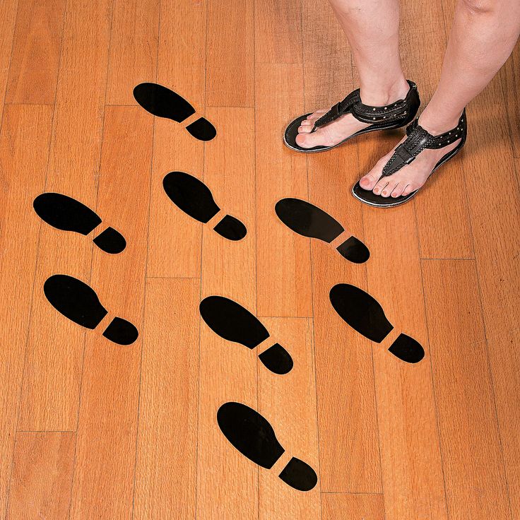 a person standing on top of a wooden floor next to black and white slippers