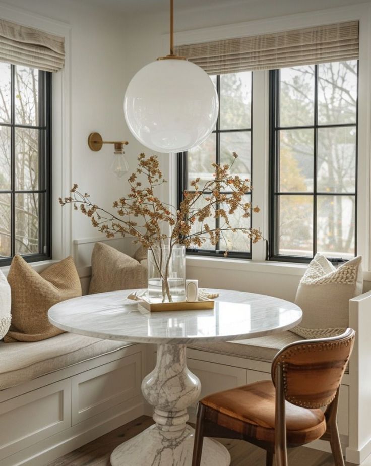 a white table and some brown chairs in a room with large windows on the wall