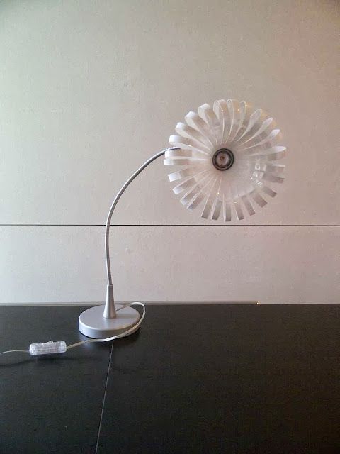 a table lamp sitting on top of a black counter next to a white wall with a clock