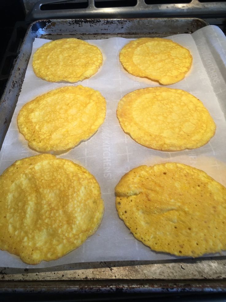 four corn tortillas sitting on top of a baking sheet next to an oven