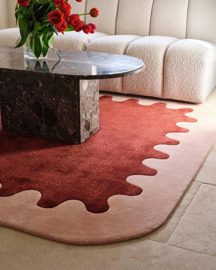 a living room with a couch, coffee table and flowers in the vase on the rug