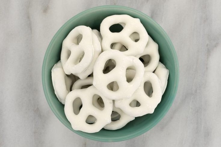 a bowl filled with white pretzels sitting on top of a marble countertop