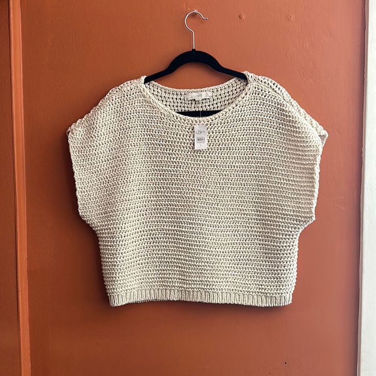 a cropped sweater hanging on a door with a hanger in front of it