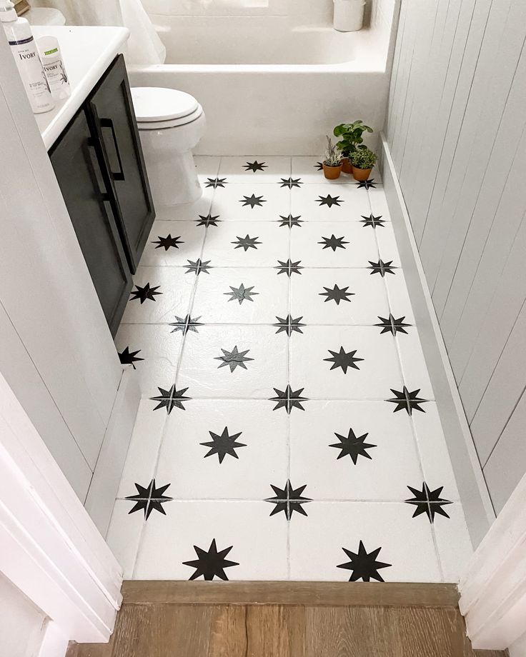 a white bathroom with black stars on the floor