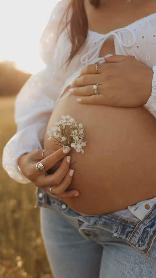 a pregnant woman holding a flower in her belly