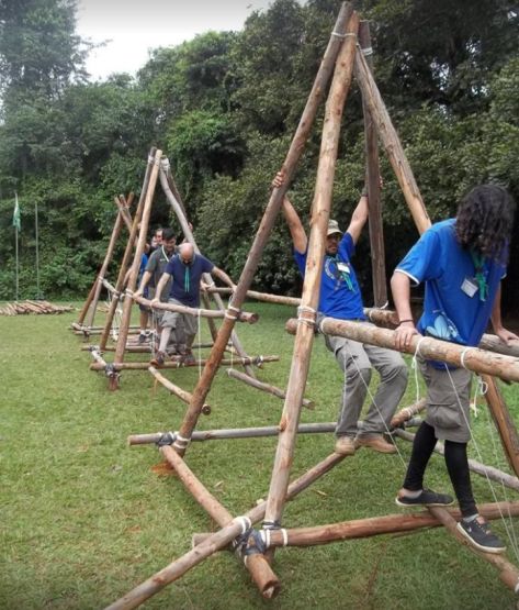 several people are playing on a wooden structure made out of sticks and wood planks