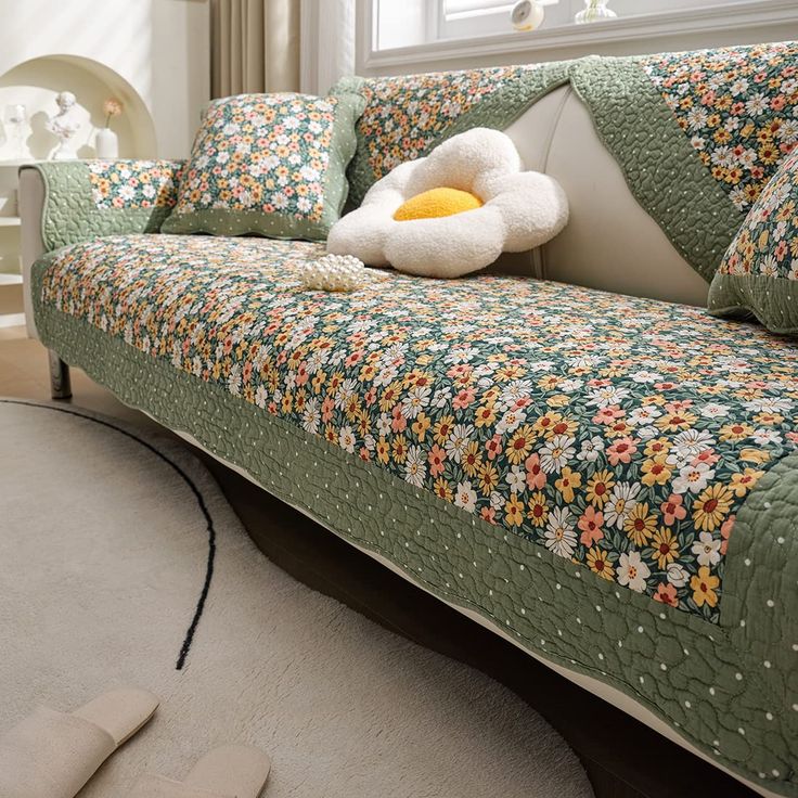 a living room with a couch covered in a flowered blanket and pillows on it