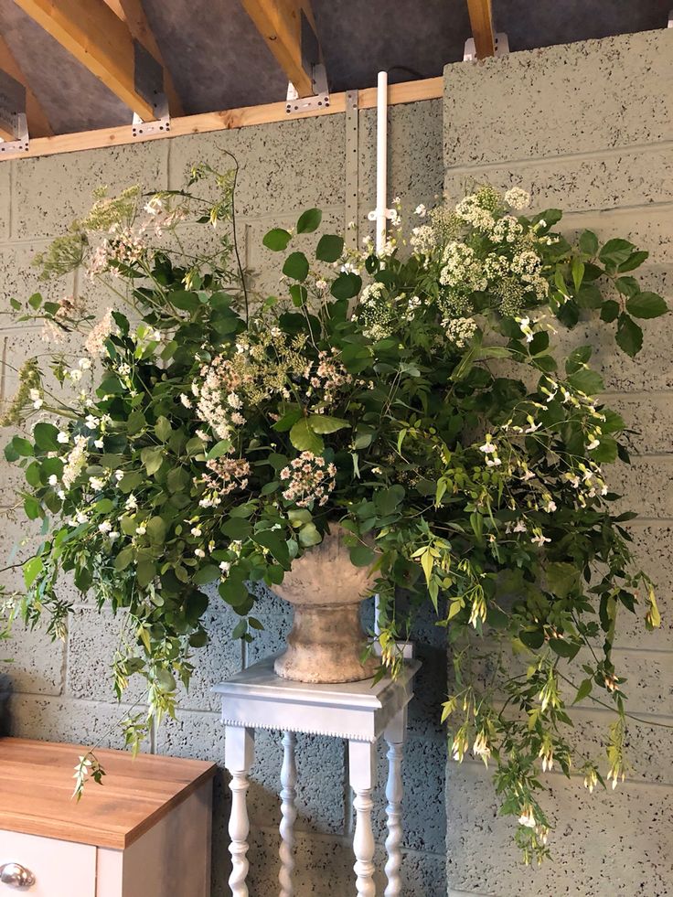 a vase filled with white flowers on top of a table next to a wooden dresser