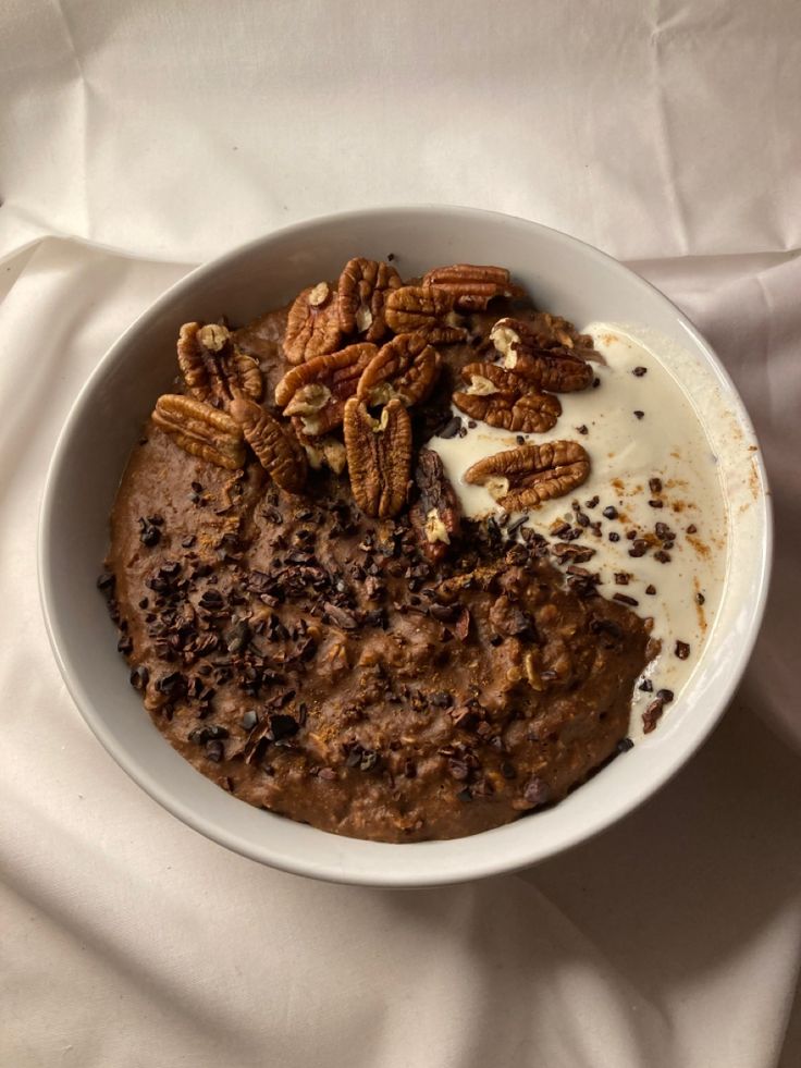 a bowl filled with oatmeal and nuts on top of a white cloth