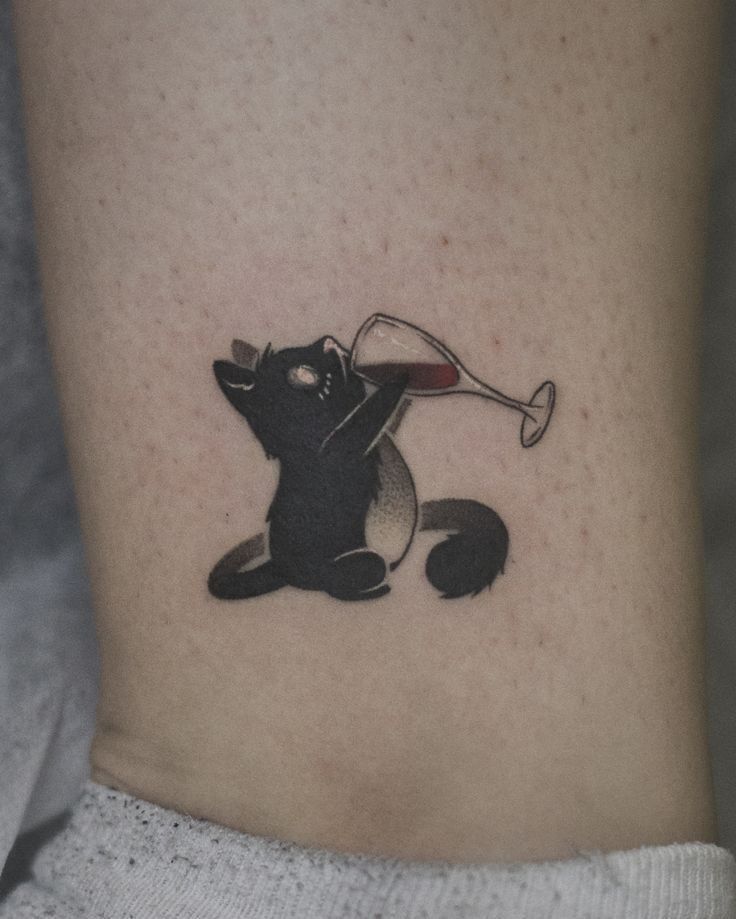 a cat with a wine glass in its mouth on the side of the ankle tattoo