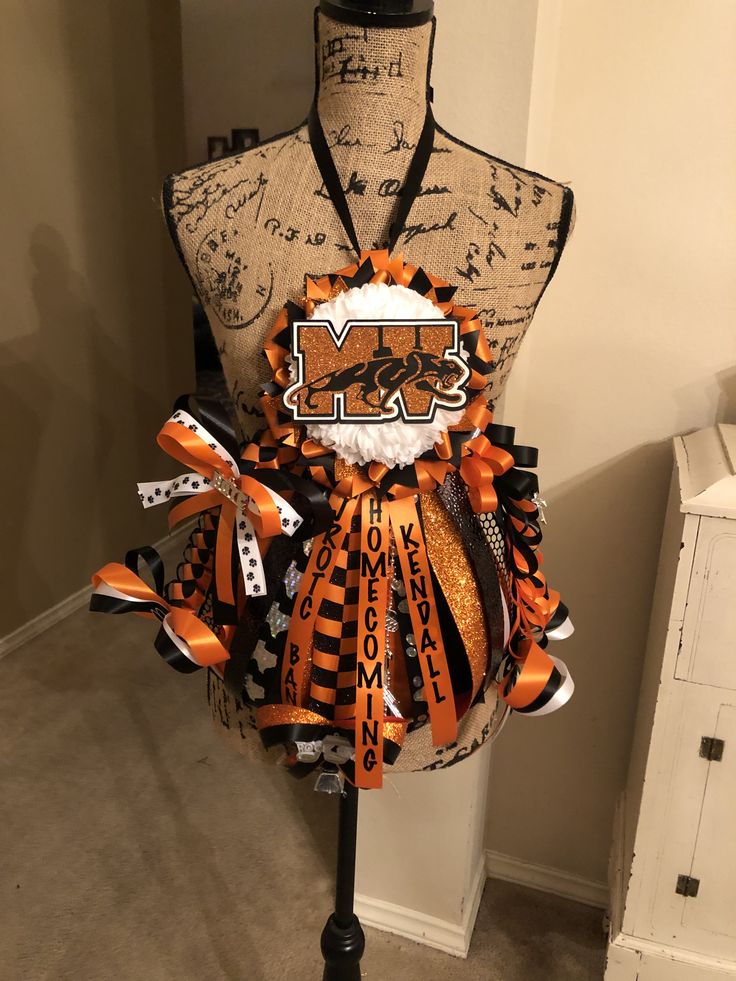 an orange and black cheer bow on a mannequin headdress for a football team