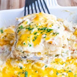 a white plate topped with mashed potatoes covered in gravy next to a fork