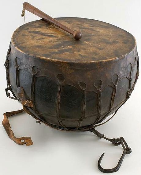 an old drum sitting on top of a white table next to a pair of scissors