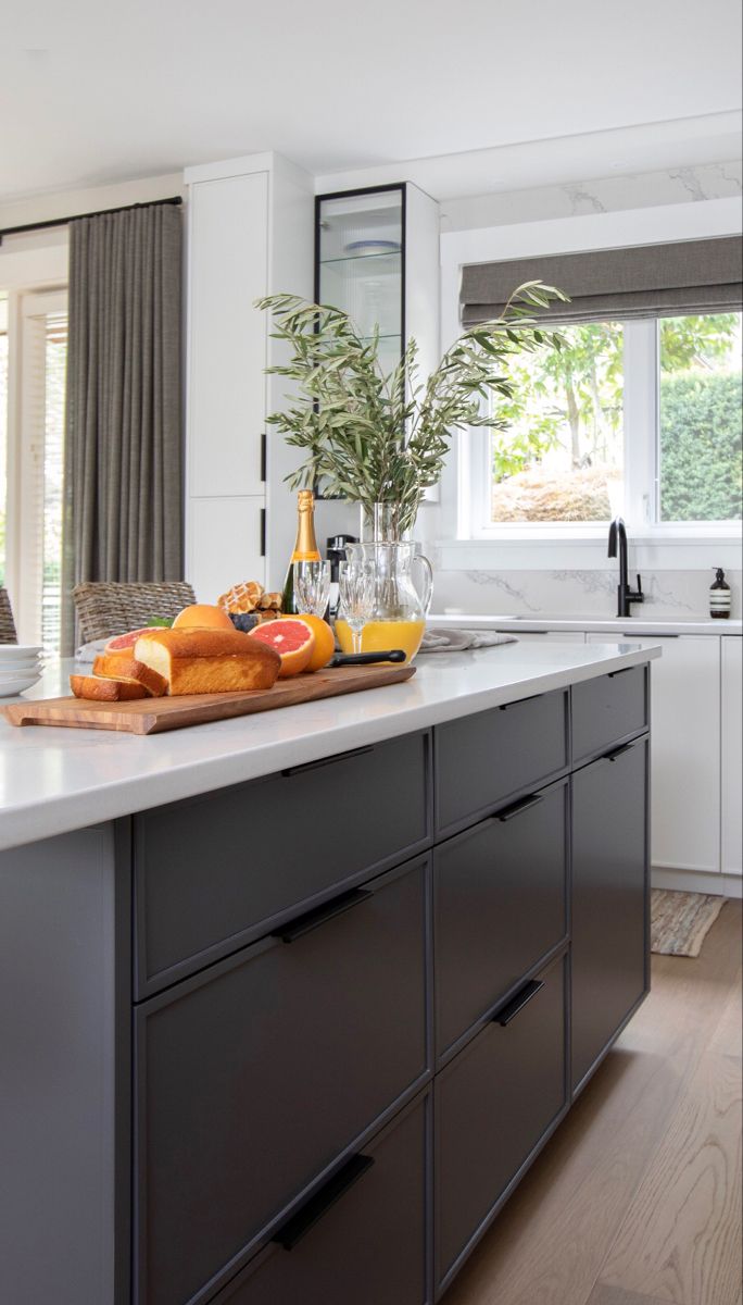 a kitchen with white cabinets and gray counter tops, along with an island in the middle