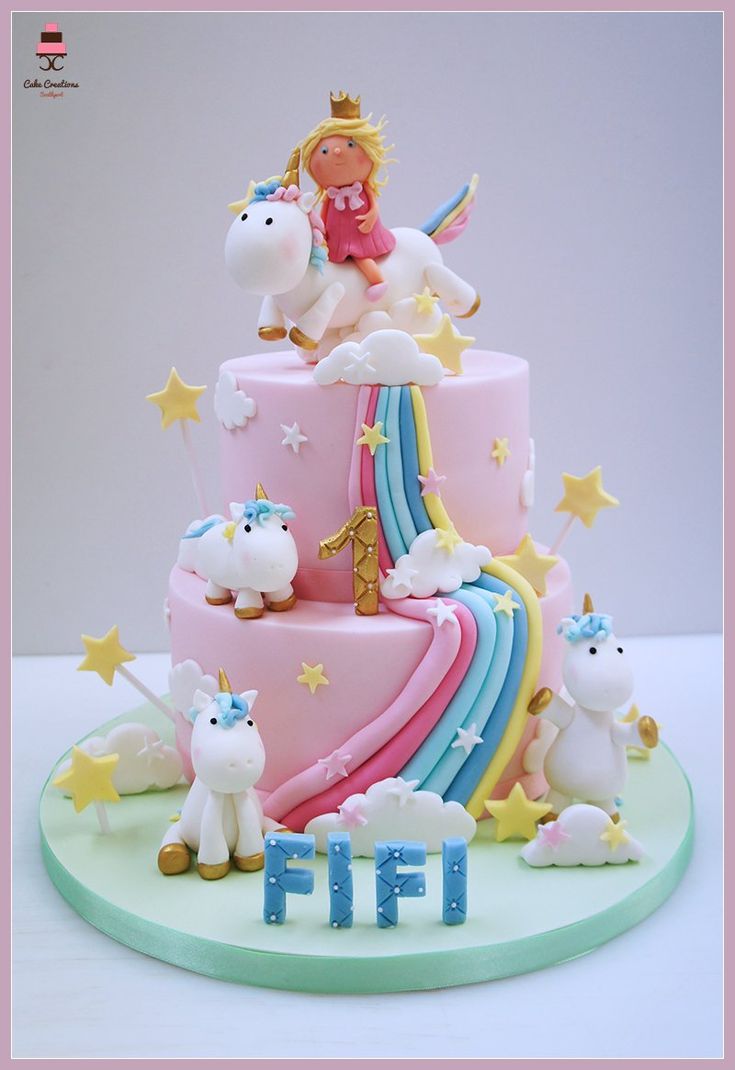 a pink cake with unicorns and stars on top is decorated in pastel colors