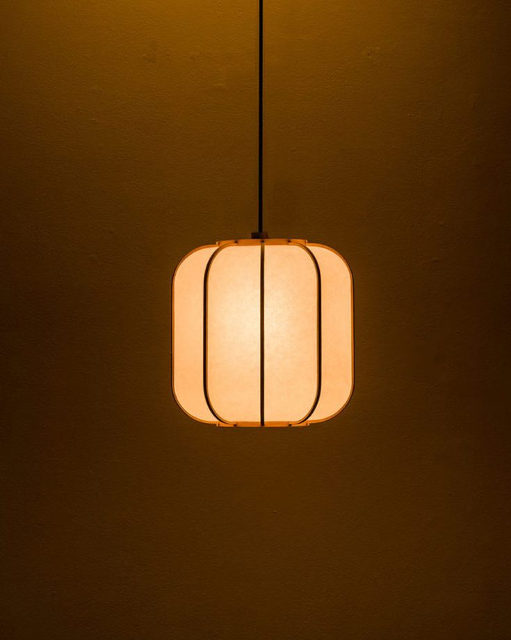 a square light hanging from a ceiling in a dimly lit room with no one around it