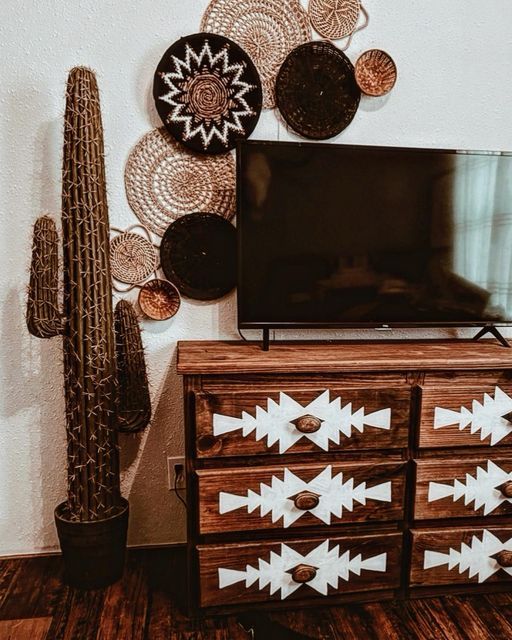 a flat screen tv sitting on top of a wooden dresser next to a cacti