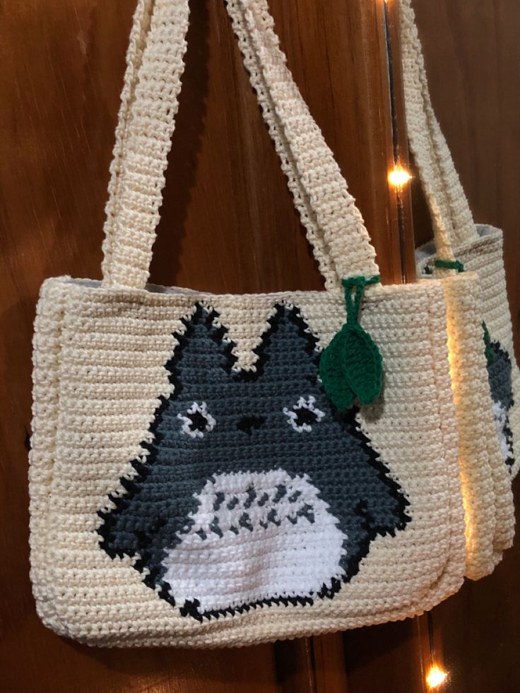 a crocheted tote bag with a cat on it hanging from a hook