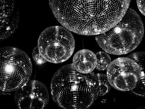 many shiny disco balls hanging from the ceiling in black and white photo with lights on them