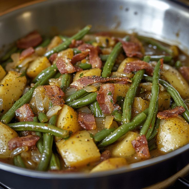 green beans, potatoes and bacon in a pan on the stove top with seasoning