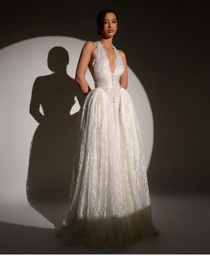 a woman in a white dress is standing with her shadow on the wall behind her