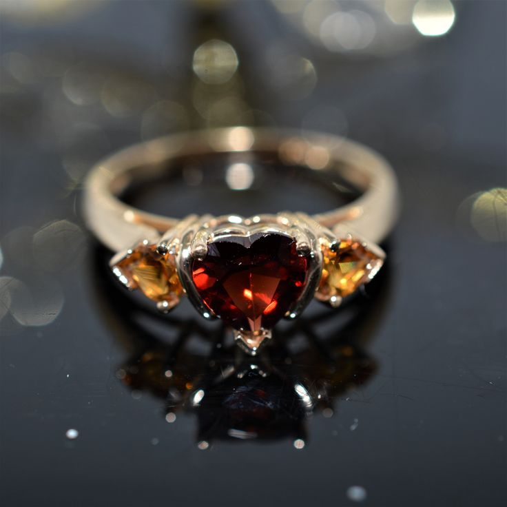 A Ladies 14K Yellow Gold Ring Set With A 6X6 Mm Heart Cut Red Garnet And 2 - 4X4 Mm Heart Cut Orange Garnets. The Ring Is Size 9 Heart Cut Multi-stone Anniversary Rings, Red Heart-shaped Rings With Center Stone, Red 14k Gold Heart Promise Ring, Red Heart Ring In 14k Gold, Red 14k Gold Heart Ring For Promise, Classic Heart-shaped Red Ruby Ring, Classic Red Heart-shaped Ruby Ring, 14k Gold Red Heart Ring For Promise, Fine Jewelry Heart Cut Multi-stone Rings