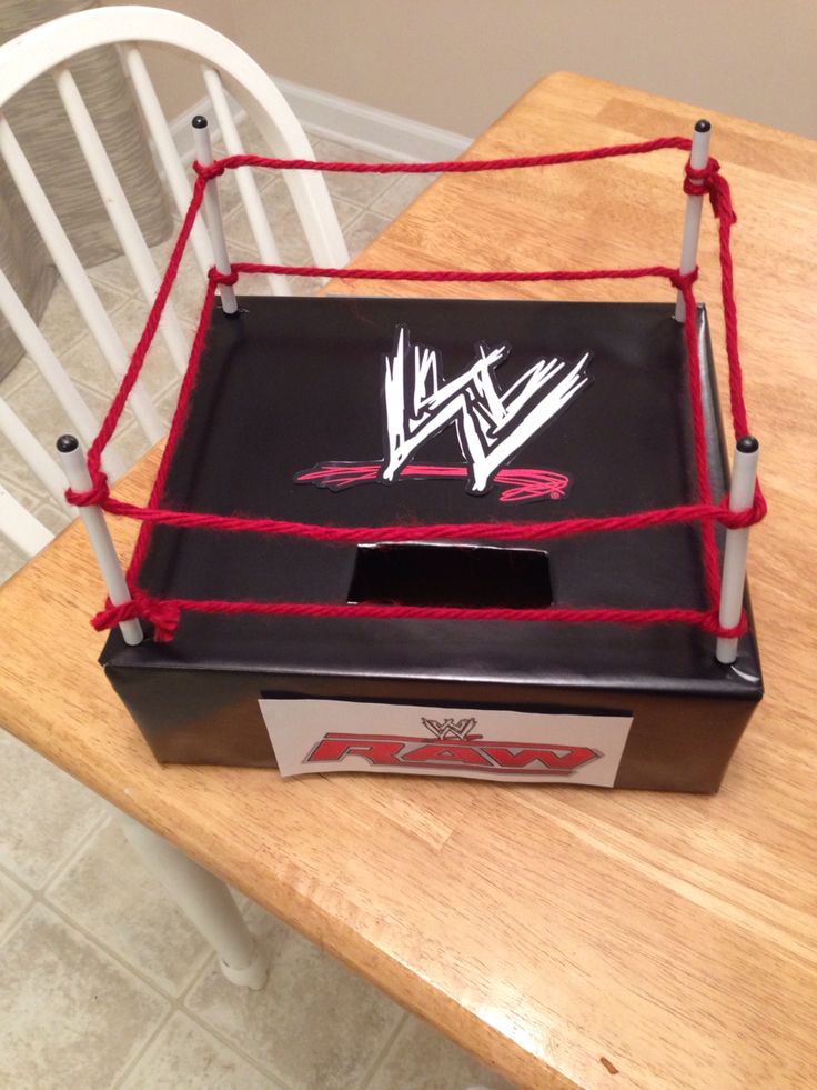 a wrestling ring cake sitting on top of a wooden table next to a white chair