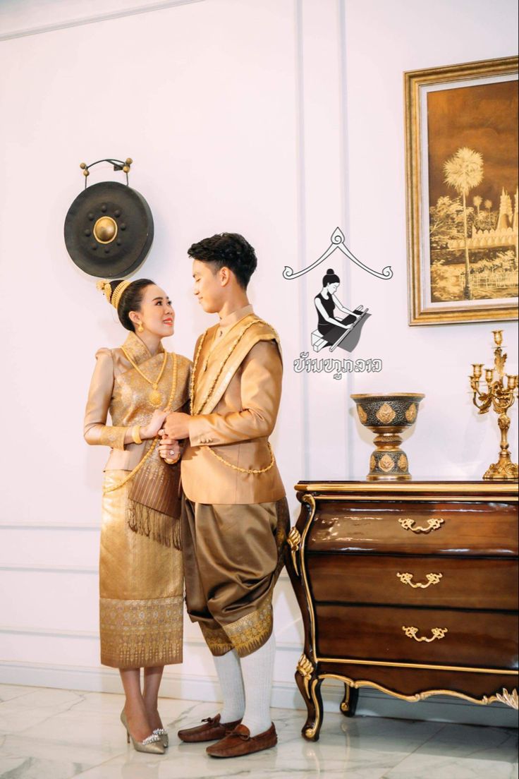 two people standing next to each other near a dresser