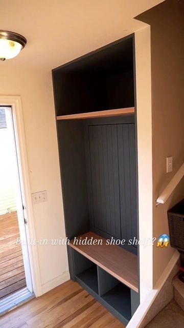 an empty room with a shelf and stairs leading to the front door that leads up to the second floor