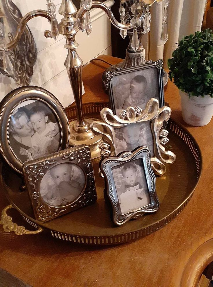 a table topped with three frames and a candle holder filled with flowers next to a potted plant