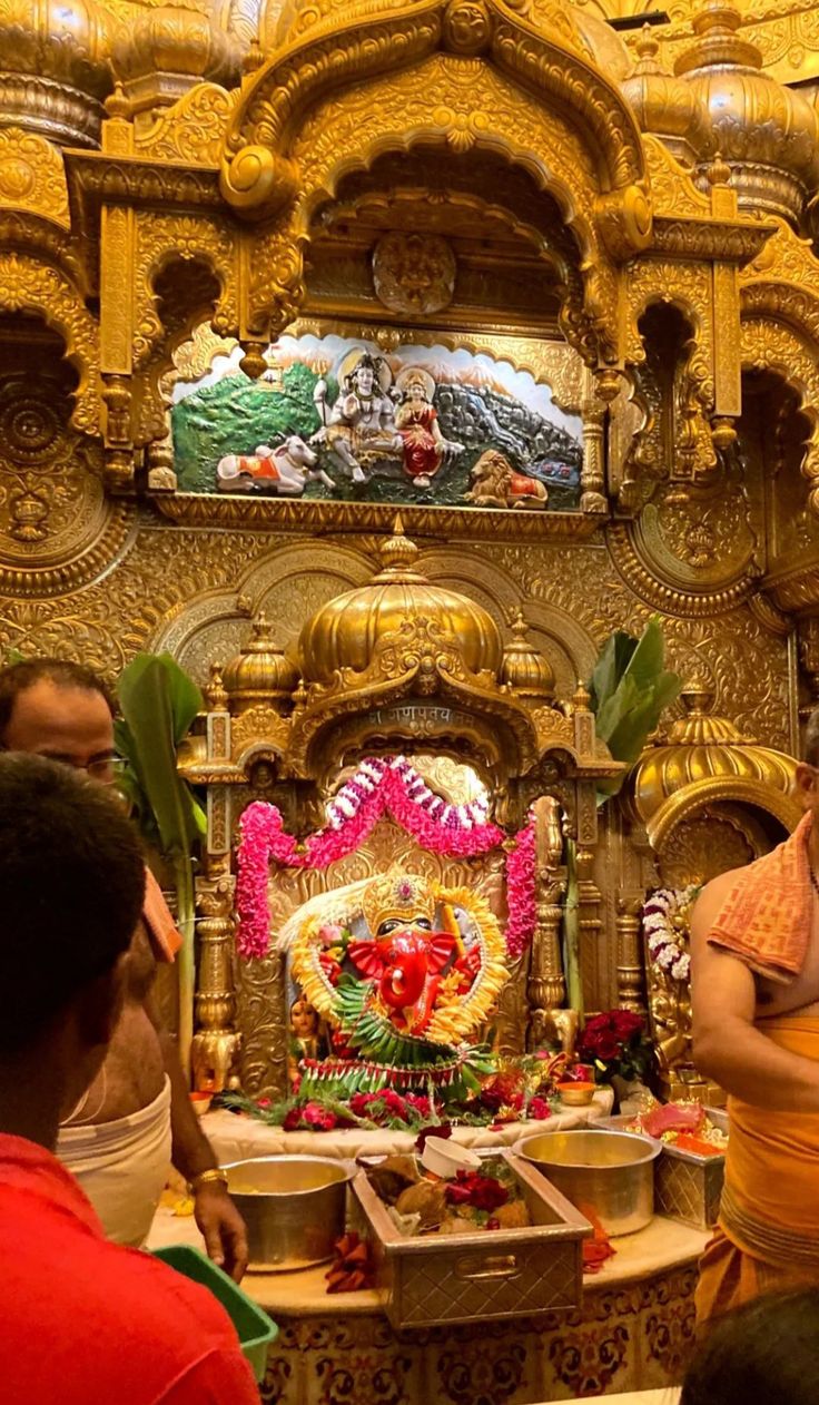 a group of people standing in front of a golden shrine with decorations on the walls