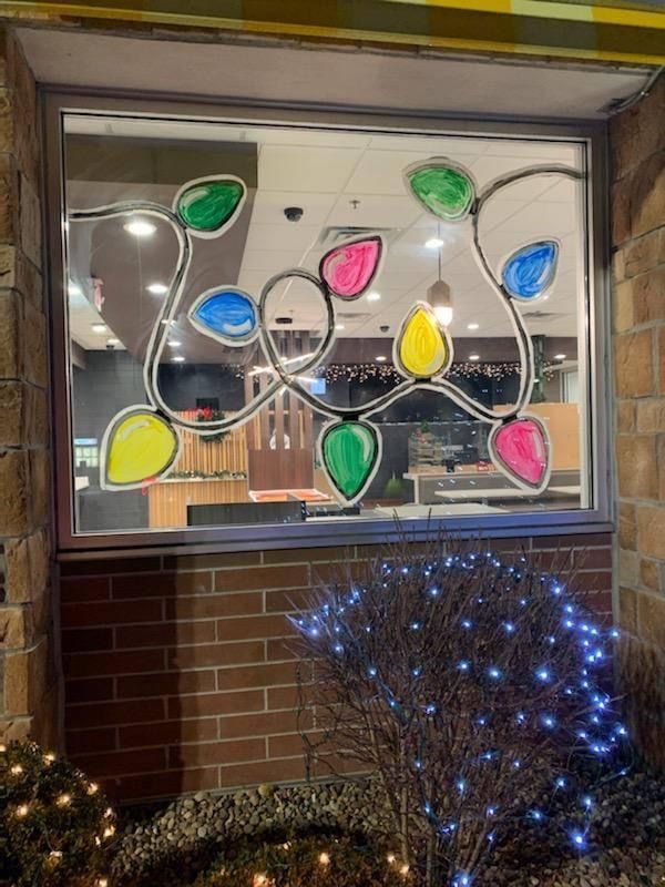 a window decorated with stained glass flowers and leaves in front of a brick building at night