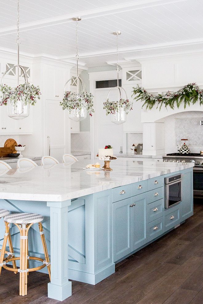 a large kitchen with blue cabinets and white counter tops is decorated with christmas greenery