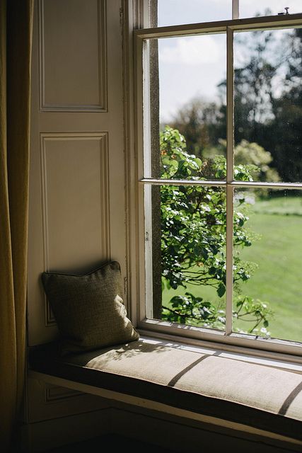 a window with a bench in front of it and a view of a green field