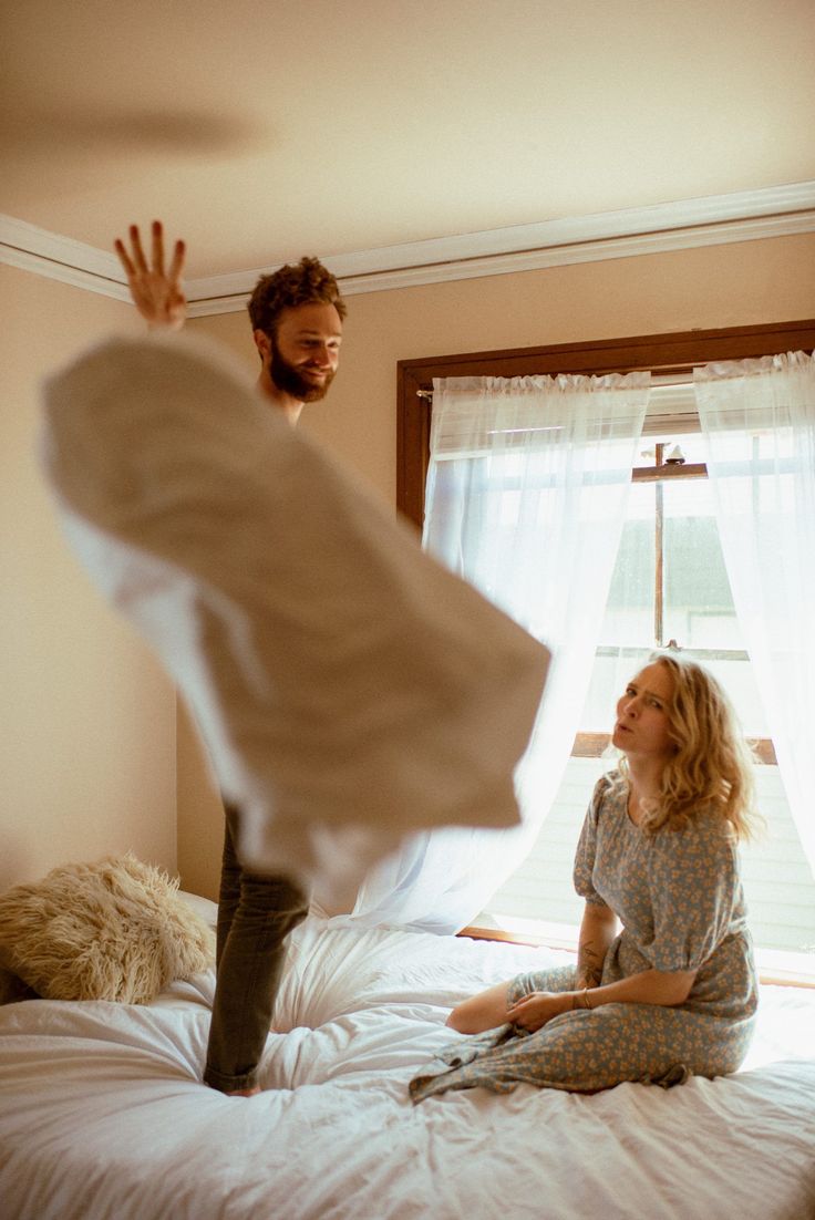 a woman sitting on top of a bed next to a man