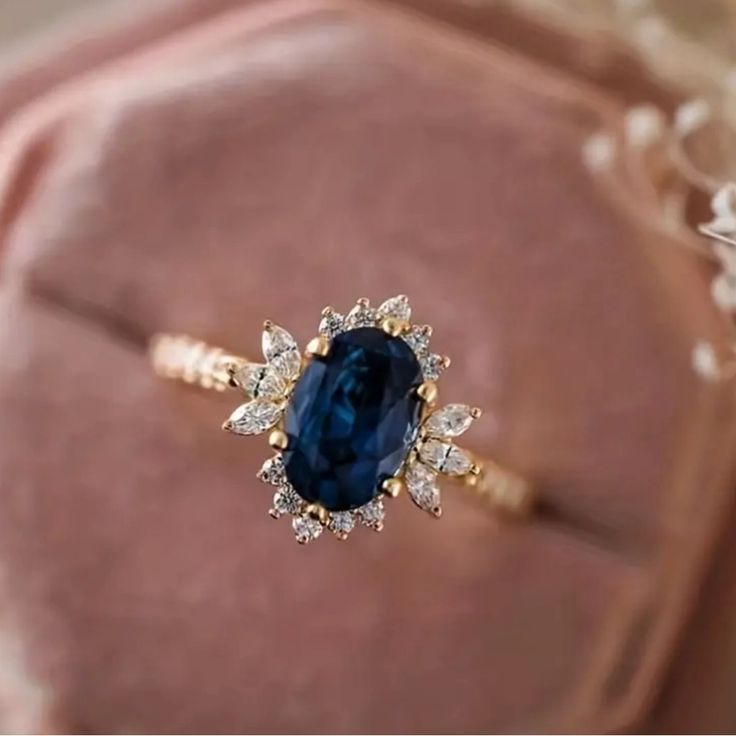 a ring with a blue stone surrounded by white and yellow diamonds on top of a pink velvet cushion