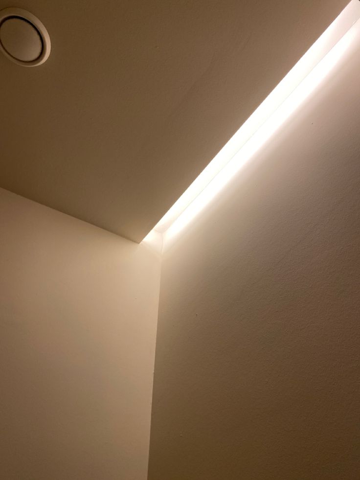 a light that is on in the corner of a room with a wall and ceiling