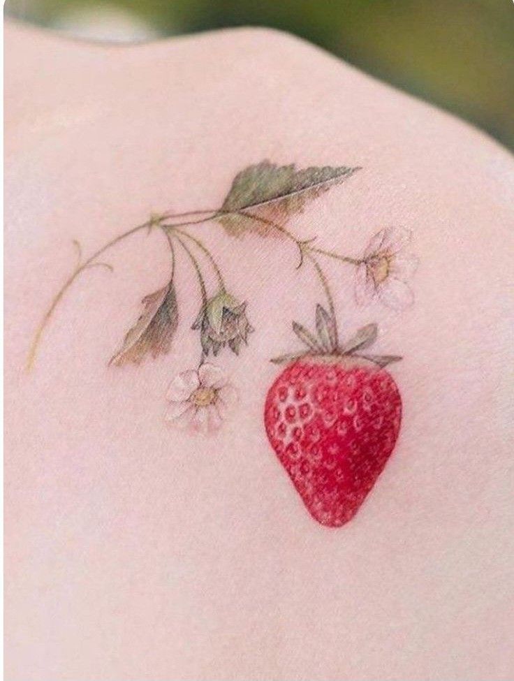 a small strawberry tattoo on the back of a woman's shoulder