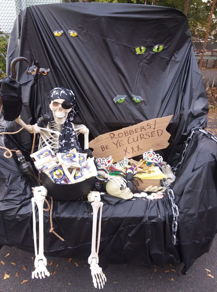 a skeleton sitting on top of a couch covered in black tarp and holding a sign