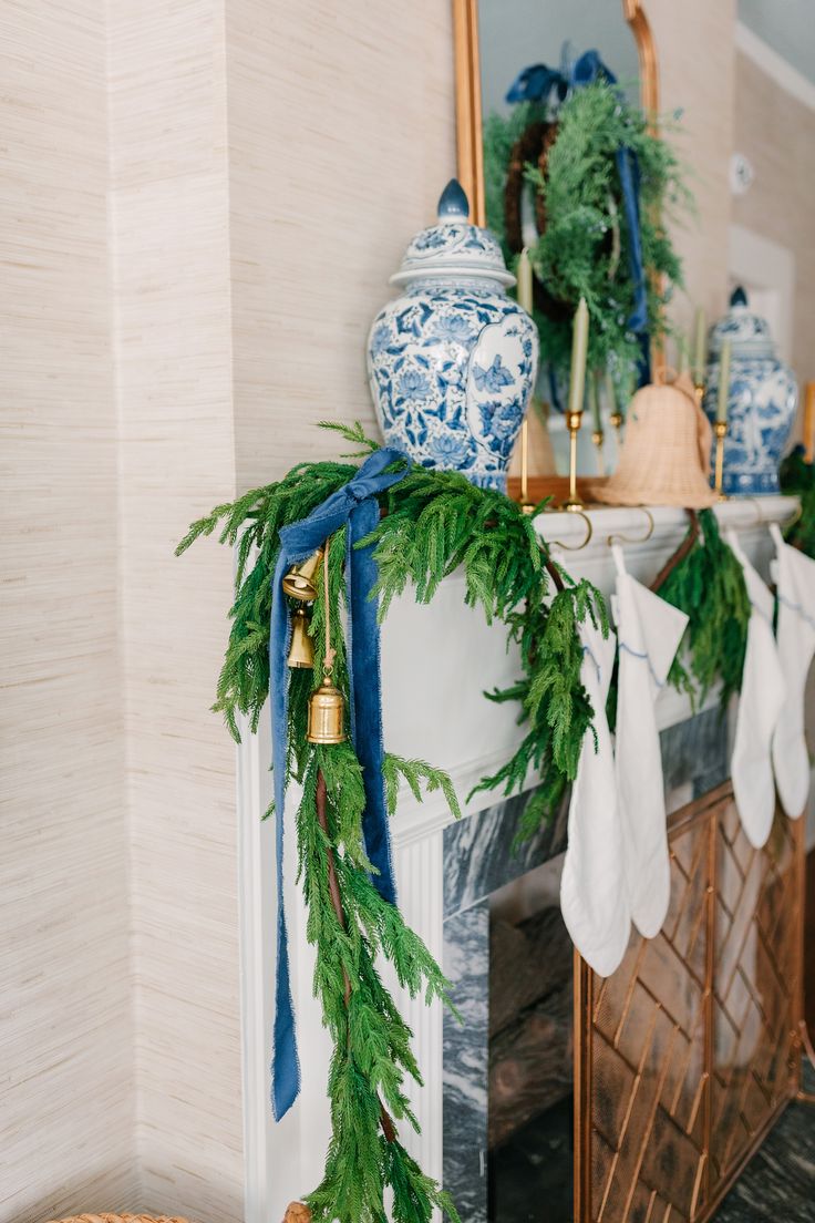 a mantel decorated with greenery and blue and white vases