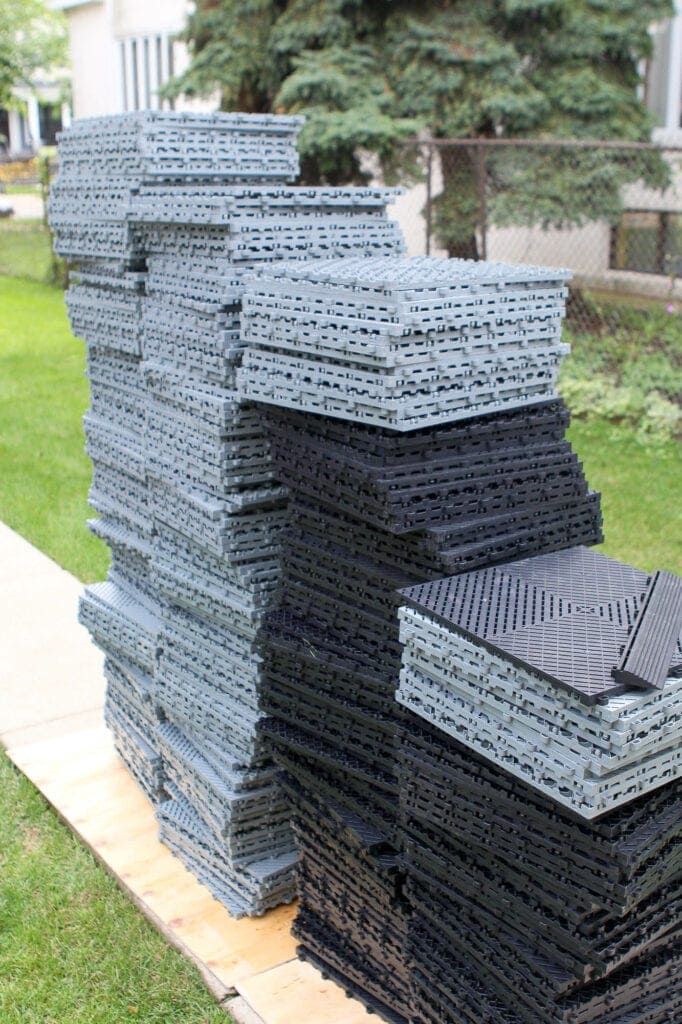 stacks of black plastic bricks sitting on top of a wooden pallet in front of a house