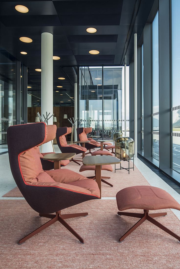 an office lobby with chairs and tables in front of large windows