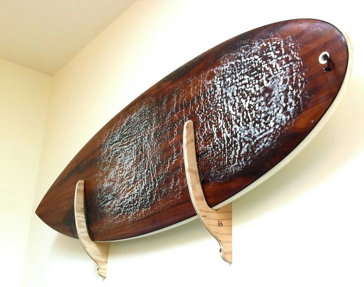 a wooden surfboard mounted to the wall with two pegs on it's sides