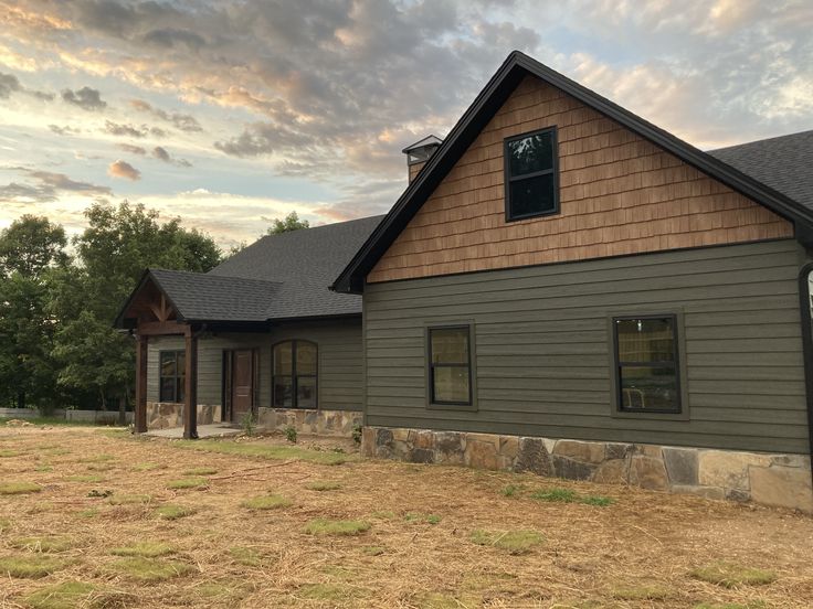 a house that is in the middle of a field with grass and trees around it