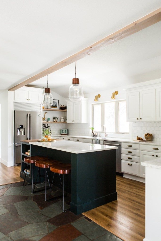 a kitchen with white cabinets and black island in the center is surrounded by wood flooring