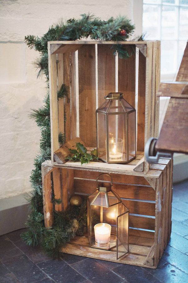 two wooden crates with christmas decorations on top and one holding a lit candle in the middle