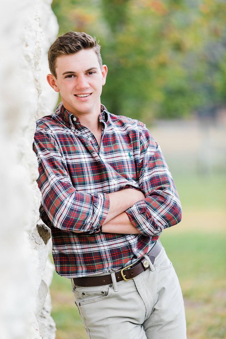 a young man leaning against a wall with his arms crossed