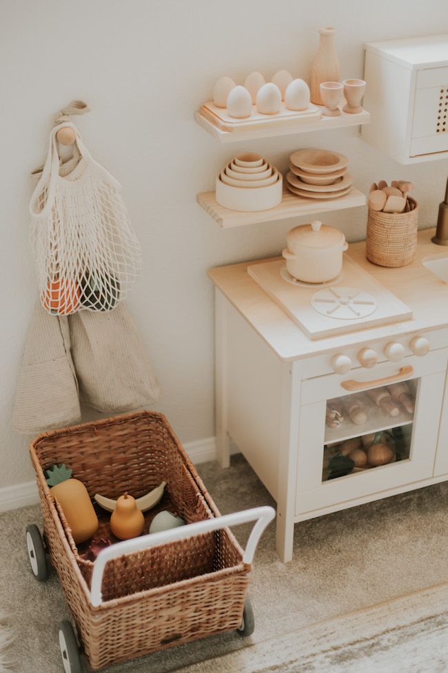 a small kitchen with white appliances and baskets on the floor next to an open microwave