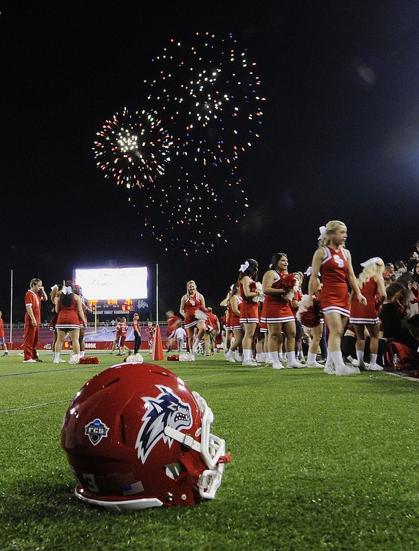 a football helmet sitting on top of a field next to a group of cheerleaders